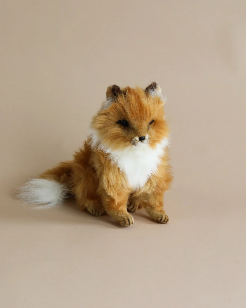 A realistic plush toy fox with fluffy fur, predominantly orange with white accents, sitting against a plain, beige background scattered with colorful Easter Basket Set - Trunks.