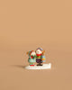 The Wee Forest Folk Tiny Collectible - The Little Wanderers features two children in winter clothes, one holding a lantern, standing together on a white base.