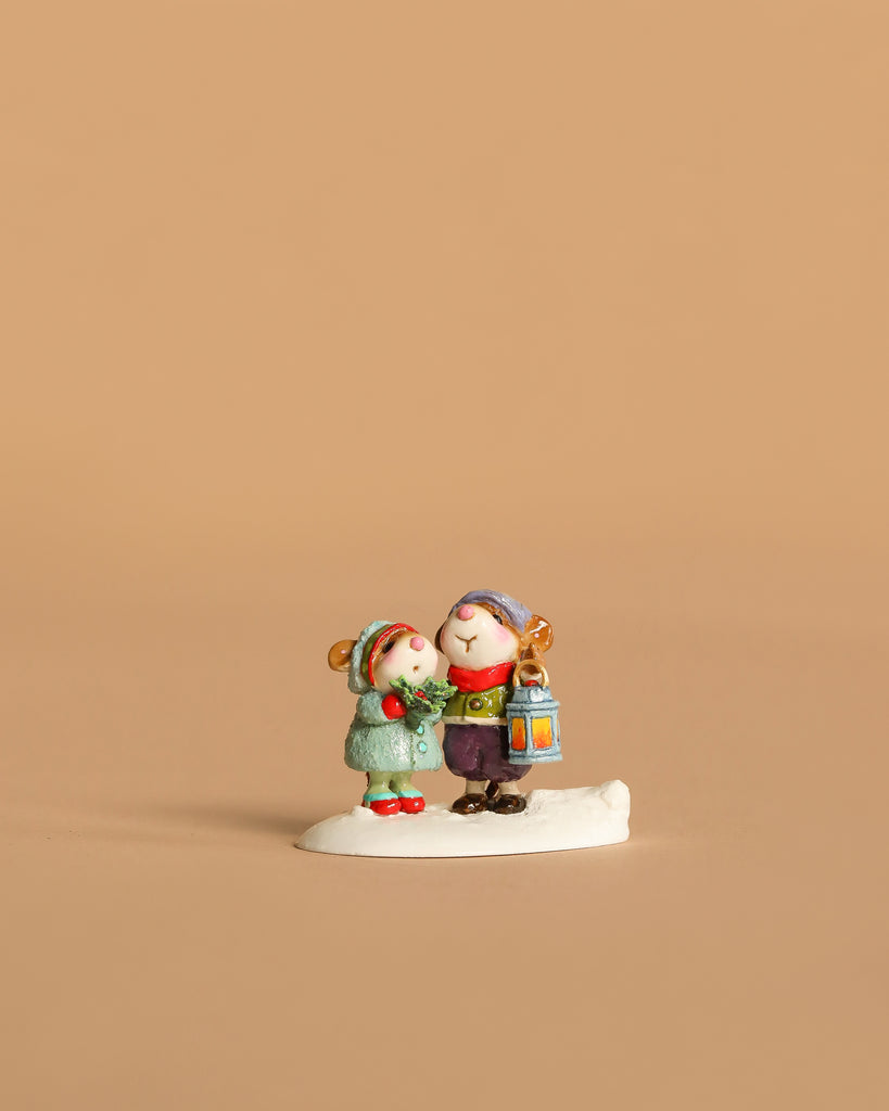 The Wee Forest Folk Tiny Collectible - The Little Wanderers features two children in winter clothes, one holding a lantern, standing together on a white base.