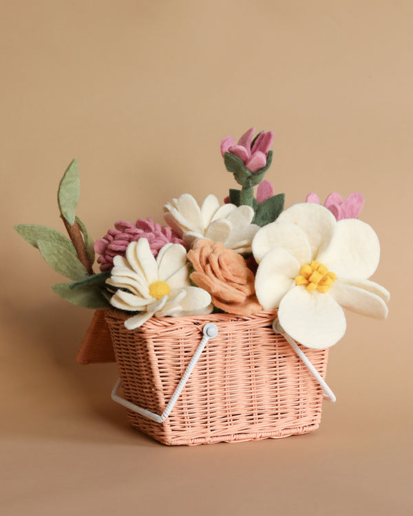 A Felt Flowers Picnic Basket with a lid adorned with an assortment of felt flowers in pastel colors, including pinks and whites, against a neutral tan background.
