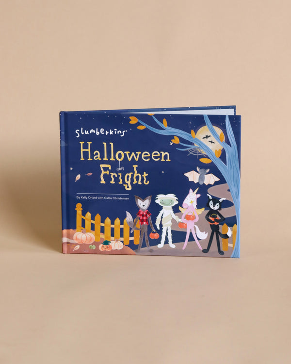 A children's book titled "Slumberkins "Halloween Fright" Hardcover Book" displayed upright against a plain beige background, showcasing colorful illustrations of whimsical creatures in spooky season costumes.