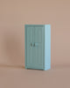 The Maileg Bedroom Set, a compact light blue cabinet with double doors and round handles, ideal for Maileg mouse furniture or storing accessories, is set against a plain beige background.