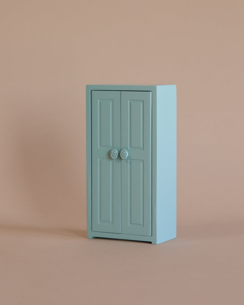The Maileg Bedroom Set, a compact light blue cabinet with double doors and round handles, ideal for Maileg mouse furniture or storing accessories, is set against a plain beige background.