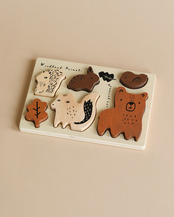 A Wooden Tray Puzzle - Woodland Animals featuring various woodland animal shapes like a bear, hedgehog, and birds, each piece uniquely painted with simple, charming details on a beige background.