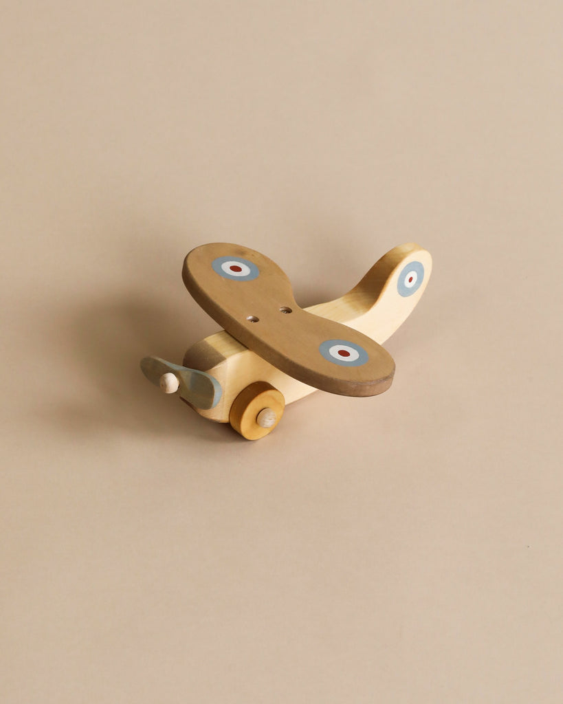 Wooden plane with light blue propeller, light brown wings with blue, white and red circles on each wing. Natural color wooden wheels. 