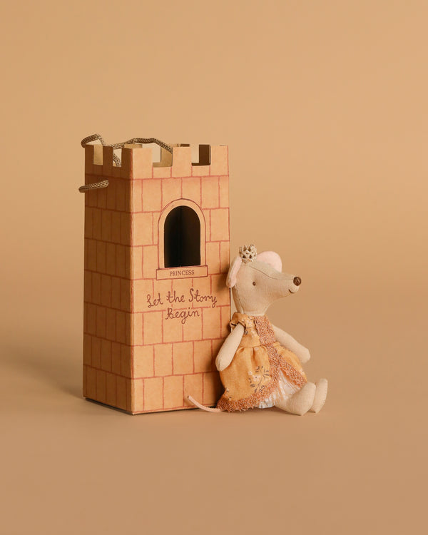 The Maileg Princess Mouse, Big Sister, wearing a dress and crown, sits beside a castle tower with "Let the Story Begin" against a beige background.
