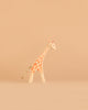 The Ostheimer Handmade Wooden Giraffe Set, featuring a small toy giraffe with orange spots and a rope tail, stands on a plain beige background and captures the delightful charm of handcrafted wooden toys.