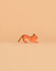 A small handcrafted wooden tiger figurine from the Ostheimer Handmade Wooden Safari Animals Set, painted with orange and black stripes, stands on a light beige background—highlighting the charm and sustainability of these unique toys.
