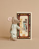 A Maileg On The Go Suitcase Set rests against a decorated matchbox featuring a vintage race car and "Mouse Race" text on the front, all set against a beige background.