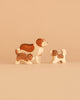 The Ostheimer Handmade Wooden Dog Family Set features three handcrafted figurines, inspired by classic Ostheimer toys and painted in white and brown. Carefully designed from sustainably sourced wood, the set includes one larger dog and two smaller ones, arranged together on a neutral beige surface to evoke a sense of family.