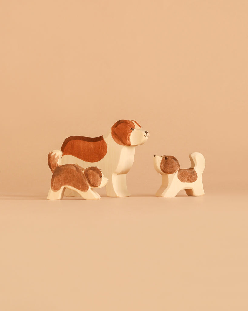 The Ostheimer Handmade Wooden Dog Family Set features three handcrafted figurines, inspired by classic Ostheimer toys and painted in white and brown. Carefully designed from sustainably sourced wood, the set includes one larger dog and two smaller ones, arranged together on a neutral beige surface to evoke a sense of family.