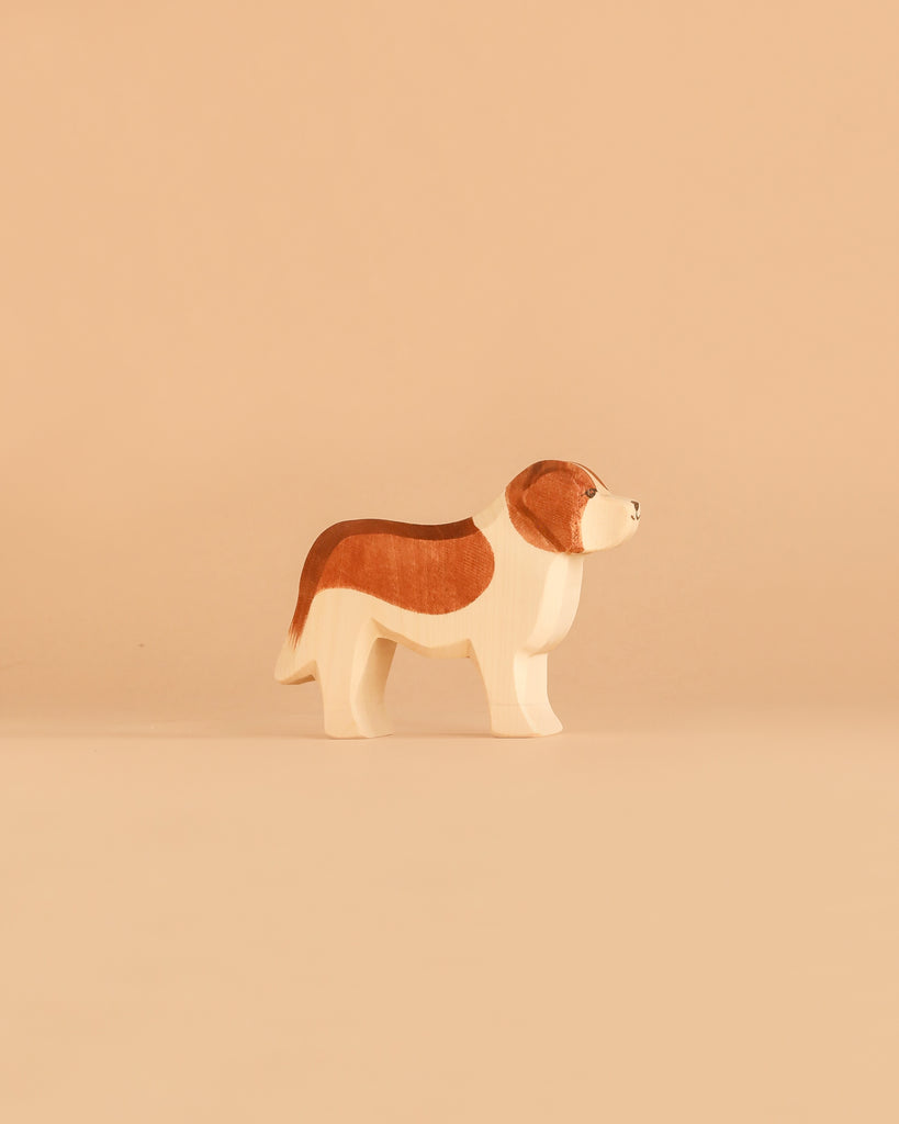 Standing on a beige background, the Ostheimer Handmade Wooden Dog Family Set features beautifully handcrafted brown and white wooden dog figurines, reflecting the quality and charm of Ostheimer toys made from sustainably sourced wood.