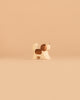 An adorable member of the Ostheimer Handmade Wooden Dog Family Set stands on a plain beige background, its minimalist, handcrafted wooden design and sustainably sourced materials echoing the charming simplicity for which Ostheimer toys are renowned.