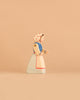 The Ostheimer Farm Wife is a handcrafted wooden figurine featuring a woman in a blue and white dress with a white bonnet covered in red dots, set against a plain beige background—an ideal collectible for those who appreciate sustainable wooden toys.