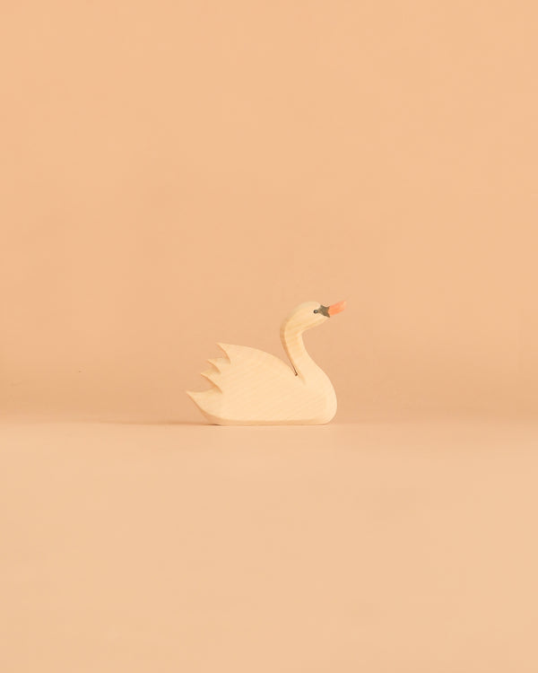 An Ostheimer Swan, Head High figurine with painted details sits on a plain peach-colored background.