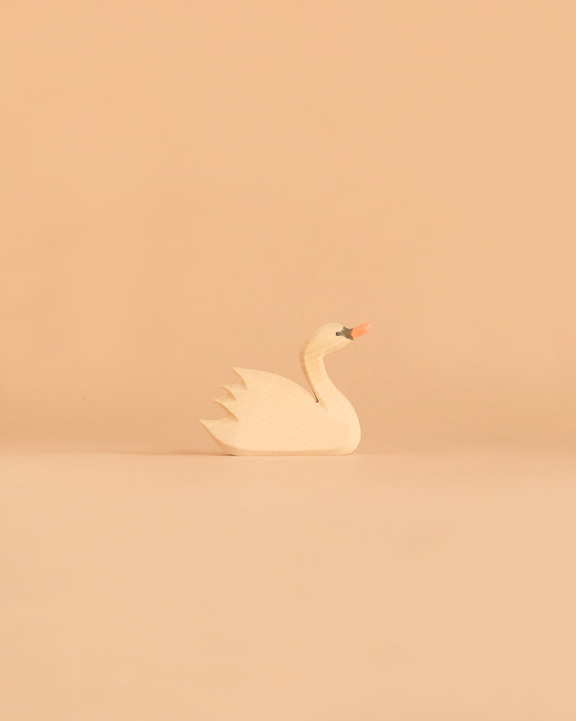 An Ostheimer Swan, Head High figurine with painted details sits on a plain peach-colored background.
