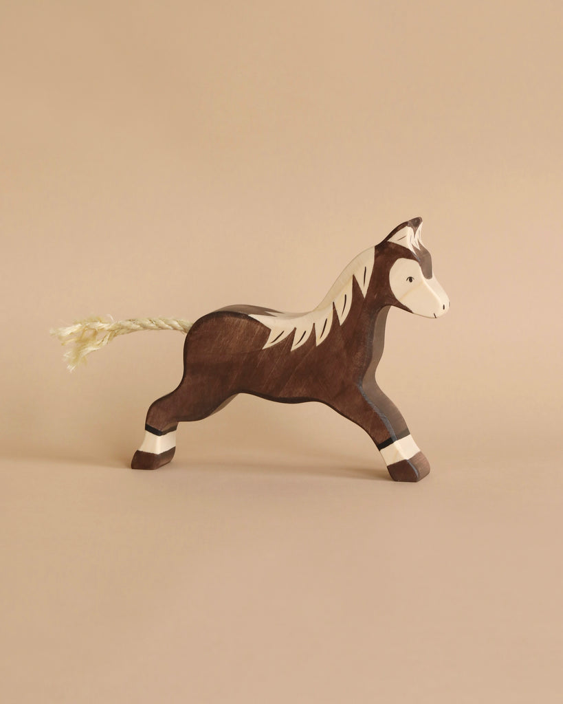 A handcrafted brown Holztiger Handmade Wooden Horses Set toy with a white mane and a rope tail.