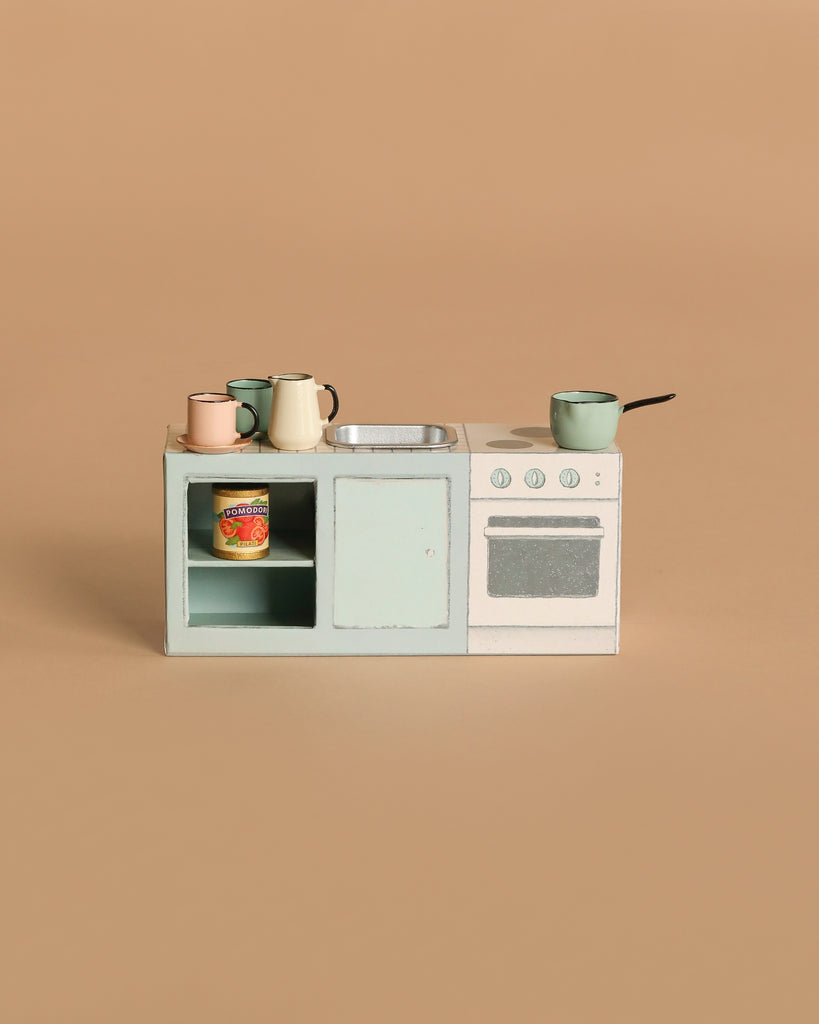 The Maileg Kitchen Counter, Mouse Size, includes a mini counter, sink, oven, and shelves with tiny pots, mugs, and a can of tomato soup—ideal for any SuitCasa mouse house.