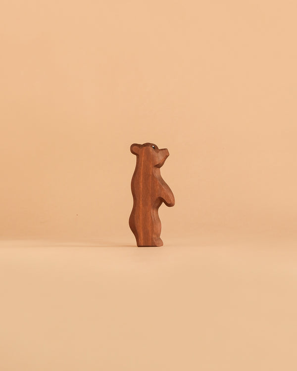 The Ostheimer Small Bear - Standing, a handcrafted wooden figurine, stands upright against a plain, light beige background.