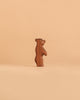 The Ostheimer Small Bear - Standing, a handcrafted wooden figurine, stands upright against a plain, light beige background.