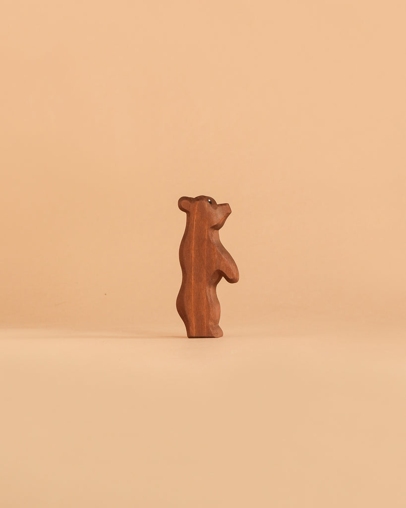The Ostheimer Small Bear - Standing, a handcrafted wooden figurine, stands upright against a plain, light beige background.