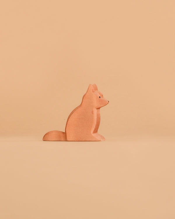 An Ostheimer Dog - Shepherd's wooden figurine sits upright against a solid light orange background.
