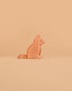An Ostheimer Dog - Shepherd's wooden figurine sits upright against a solid light orange background.
