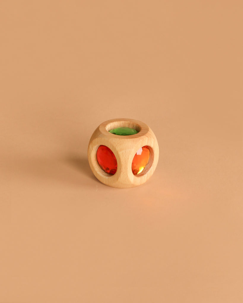The Easter Basket Gift Set features a small round wooden toy with circular cutouts holding red and green translucent gems, displayed on a light brown surface against a plain beige background.