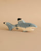 The Holztiger Handmade Wooden Sea Animals Set features a blue, white, and black shark figurine resting on a beige surface with a matching background, showcasing the charm of minimalist, handcrafted wooden toys.