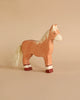 The Holztiger Handmade Wooden Farm Animals Set features a handmade wooden toy horse with a light brown body, white mane and tail, and white-red leg markings—ideal for any wooden animal set or Holztiger collection.