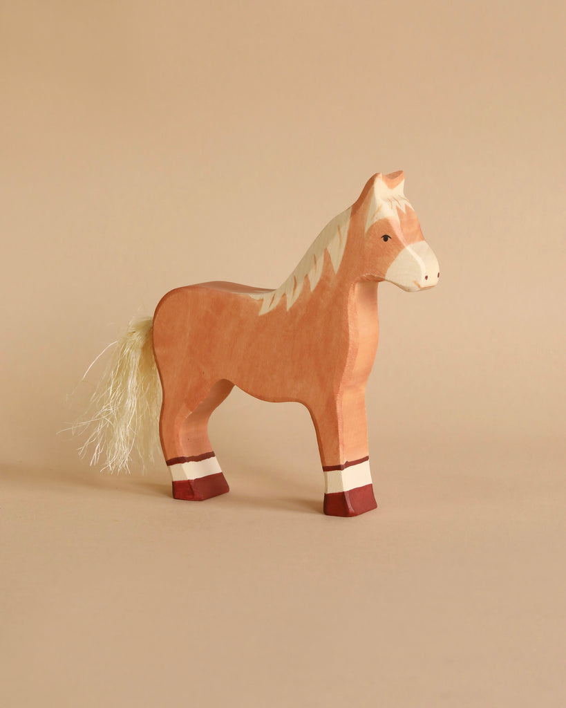 The Holztiger Handmade Wooden Farm Animals Set features a handmade wooden toy horse with a light brown body, white mane and tail, and white-red leg markings—ideal for any wooden animal set or Holztiger collection.
