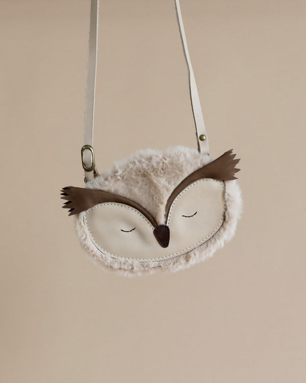 A Donsje Britta Exclusive Purse - Owl with a premium leather white body, brown wings, and closed eyes, suspended against a neutral beige background.