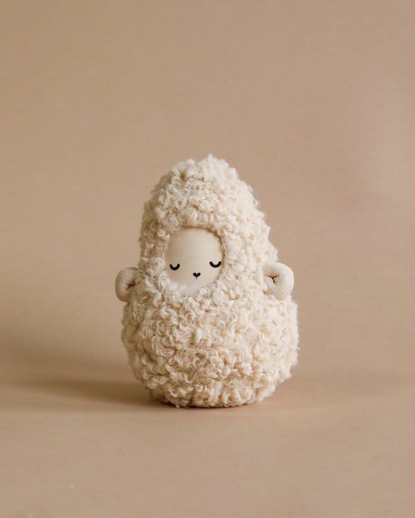 A Handmade Musical Roly Poly - Lamb resembling a fluffy sheep with a serene facial expression, curly textures, and tiny ears, emitting gentle musical sounds, against a soft beige background.