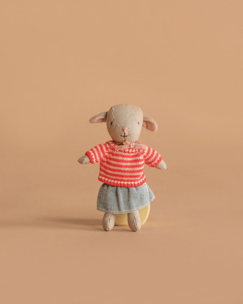 The Maileg Easter Egg with Lamb & Extra Clothing features a small stuffed lamb in a red and white striped sweater and gray skirt, posed upright against a plain light brown background.