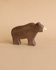 A simple, handcrafted wooden bear from the Holztiger Handmade Wooden Woodland Animals Set stands on a beige surface with a matching background—painted brown with a light snout, ideal for open-ended play and classic in style.