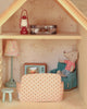 The Maileg Fully Furnished Farmhouse Set + Surprise Gift (ships in one week) creates a charming miniature living room, featuring a mouse doll in a striped shirt relaxing on a blue armchair, surrounded by delightful Maileg Mouse Furniture including a polka-dot sofa, tiny TV, lamp, and an accessorized shelf with items like a lantern and suitcase displayed above.