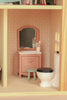Experience the charm of the Maileg Fully Furnished Farmhouse Set + Surprise Gift (ships in one week), featuring a miniature bathroom complete with Dollhouse Accessories—a pink vanity, mirror, green stool, cups with toothbrushes, and a white toilet with a black lid. Perfectly sized for your Maileg Mouse Furniture or to complete your Maileg Farmhouse Dollhouse, this set’s walls are adorned with a stylish geometric pattern.