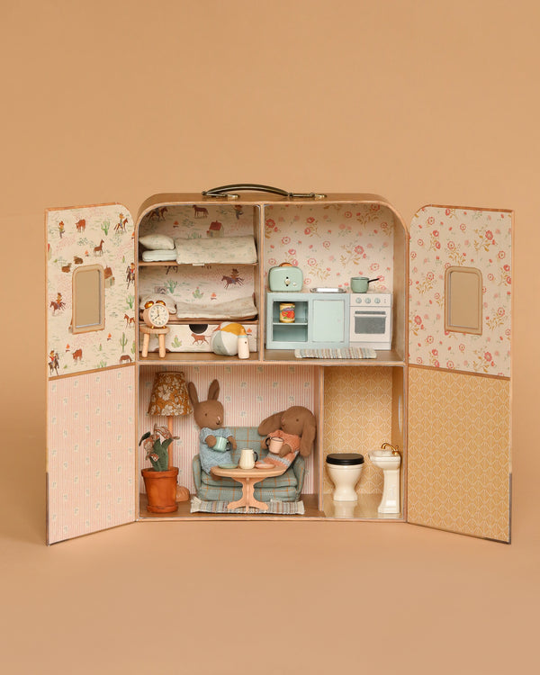 The Maileg Fully Furnished Suitcasa with Micro Bunny Set opens like a suitcase to reveal a dollhouse with a bunk bed, kitchen, and table, complete with cute furniture, decor, and a Micro Bunny.