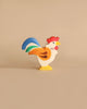 Handmade Holztiger wooden rooster toy from the Holztiger Handmade Wooden Farm Animals Set with red, orange, green, and blue painted details.