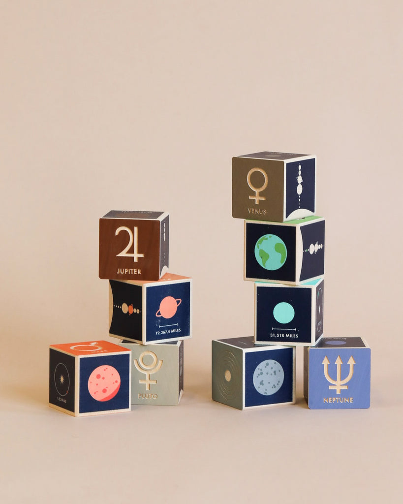 A collection of colorful, educational Uncle Goose Planet Blocks with solar system themes, including Venus, Jupiter, and Neptune, set against a light beige background.