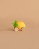 Lou The Lemon Baby Car, an eco-friendly toy shaped like a yellow lemon with green leaves and two round wooden wheels, is set against a plain beige background.