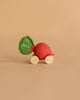 Betty The Beetroot Baby Car, an eco-friendly toy with a red beetroot shape, green leaves, and four wooden wheels, is shown on a plain beige background.