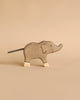 A simple wooden elephant with carved details and a short black tail stands on a beige background. Part of the Holztiger Handmade Wooden Safari Animals Set, it showcases signature craftsmanship and light-colored feet.