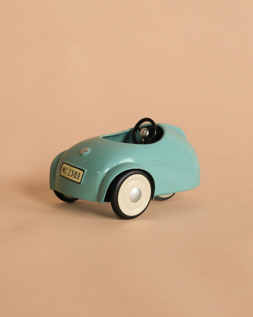 The Maileg Mouse Car - Light Blue is a vintage-style metal pull toy with white wheels and a black steering wheel. It features a "MC 2389" license plate and is ideal for imaginative mouse adventures.