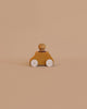 The Lubulona Wooden Car with Figure - Ochre is a small eco-friendly toy featuring white wheels and a round peg figure on top, displayed on a plain beige background.