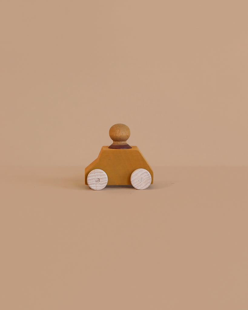 The Lubulona Wooden Car with Figure - Ochre is a small eco-friendly toy featuring white wheels and a round peg figure on top, displayed on a plain beige background.
