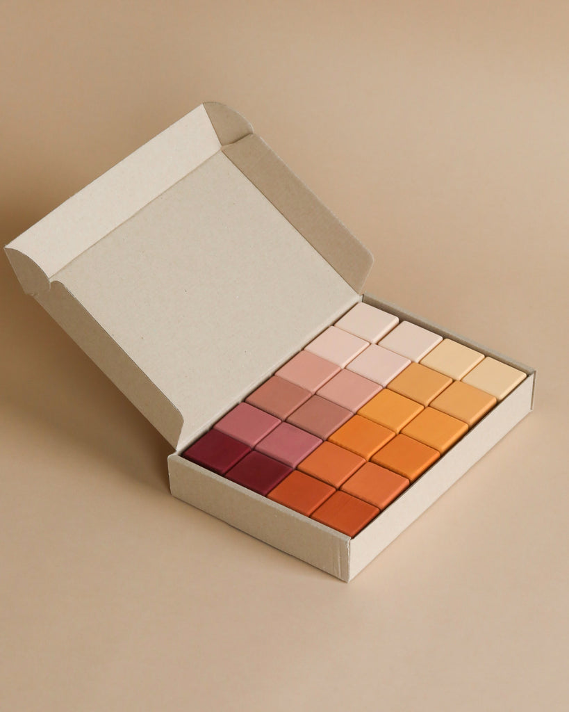 A palette of assorted warm-toned eyeshadows in shades of pink, orange, and brown, displayed with Wooden Blocks - Marsala paint in an open cardboard box on a beige background.