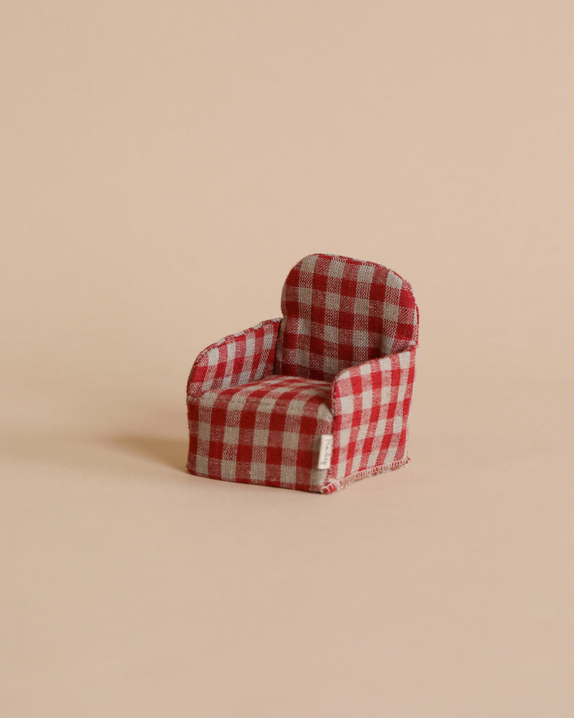 A miniature Maileg Plaid Chair with red and white checkered fabric on a plain beige background.