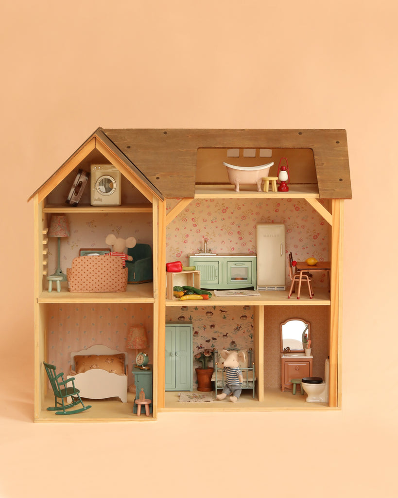 The Maileg Fully Furnished Farmhouse Set + Surprise Gift features a charming wooden dollhouse with four beautifully decorated rooms, complete with adorable miniature furniture and animal figurines. It includes delightful Maileg Mouse Furniture and a variety of dollhouse accessories for the kitchen, bathroom, bedroom, and living area—all presented against a soft peach background.