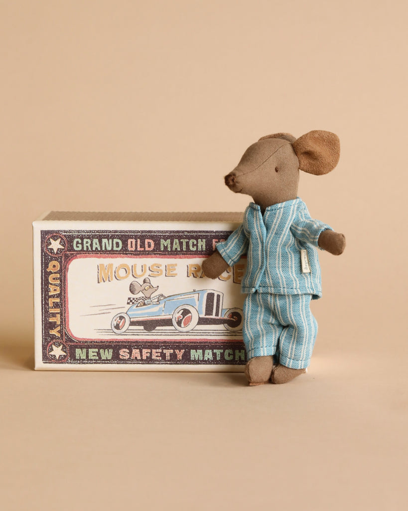 A Maileg Big Brother Mouse in Box toy in a striped blue pajama standing next to a vintage matchbox illustrated with a mouse riding a car.